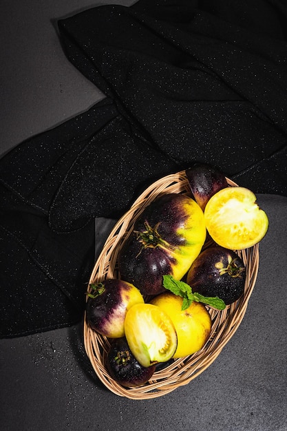 Variedad de tomates Yellowviolet Colores primarios en una cesta de mimbre Cosecha de verduras maduras