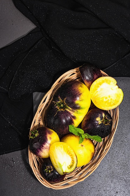 Variedad de tomates Yellowviolet Colores primarios en una cesta de mimbre Cosecha de verduras maduras