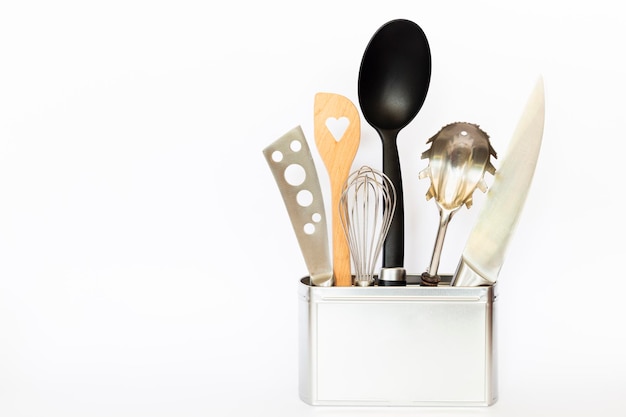 Foto una variedad de utensilios de cocina y herramientas de cocina en una caja de metal de color plateado sobre fondo blanco