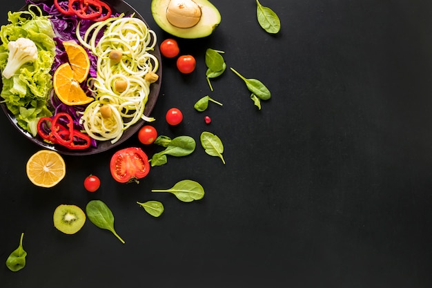 Foto variedad de verduras y frutas frescas picadas sobre fondo negro