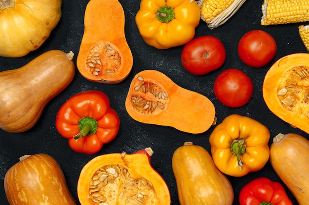 Variedad de verduras maduras como calabaza y maíz en la mesa oscura