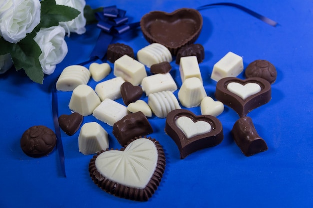 Variedade de bombons de chocolate doce e rosas brancas para a celebração do dia branco