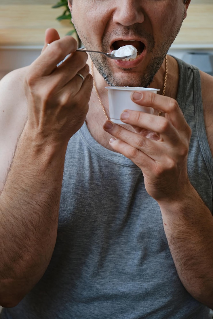 Variedade de café da manhã saudável Iogurte com frutas e sementes Homem comendo iogurte na mesa na cozinha Close-up de um homem irreconhecível