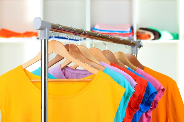 Foto variedade de camisetas casuais em cabides de madeira