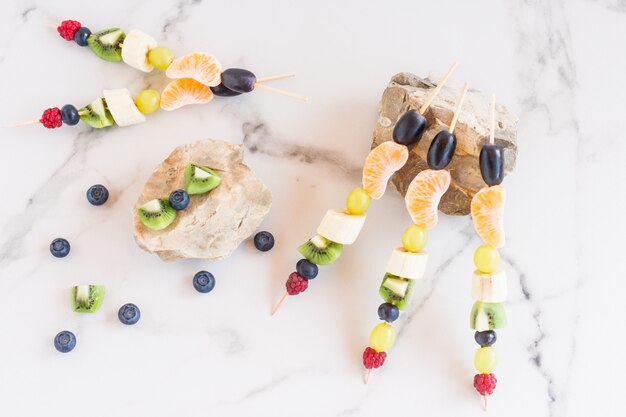 Variedade de canapés de frutas em pedras, fundo de mármore branco. vitaminas vegetais.