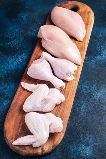 Variedade de carne de frango Partes cruas sobrecoxa peito filé asas coxa Fundo azul Vista superior