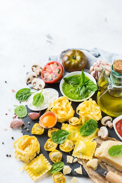 Variedade de comida italiana e ingredientes ravioli com ricota e espinafre macarrão tortellini pesto molho de tomate azeite queijo parmesão Copie o fundo do espaço