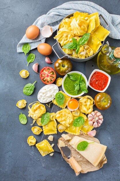 Variedade de comida italiana e ingredientes ravioli com ricota e espinafre macarrão tortellini pesto molho de tomate azeite queijo parmesão Vista superior plana lay