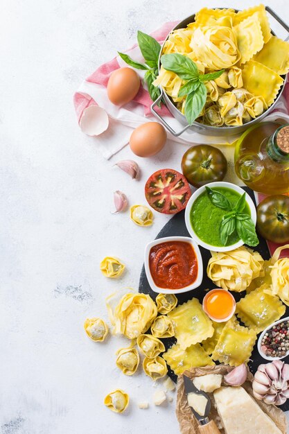 Variedade de comida italiana e ingredientes ravióli macarrão espaguete pesto molho de tomate azeite queijo parmesão Vista superior plano leigo fundo