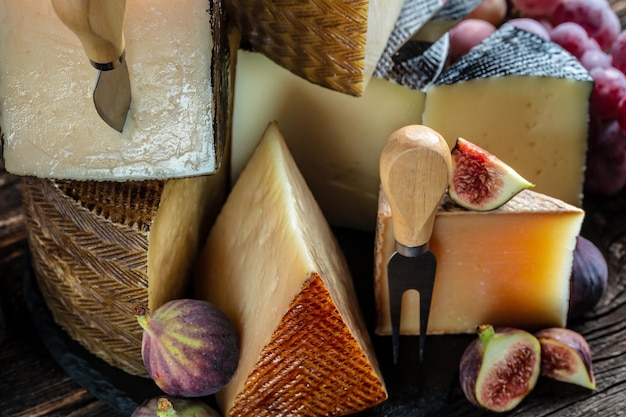 Variedade de diferentes tipos de queijo com uvas e figos Fundo de queijo pedaços tradicionais de queijo espanhol francês Itália