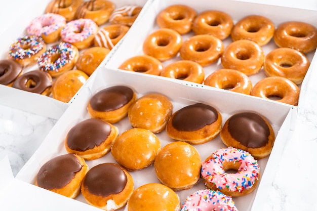 Variedade de donuts comprados em uma caixa de papel branco.