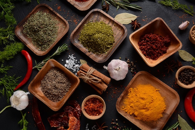 Variedade de especiarias e ervas na mesa da cozinha. Várias ervas e especiarias coloridas para cozinhar em fundo escuro