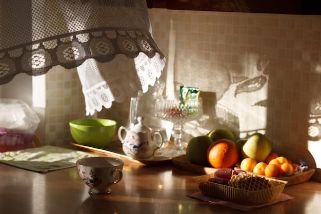 Variedade de frutas com chaleira e xícara na mesa na cozinha