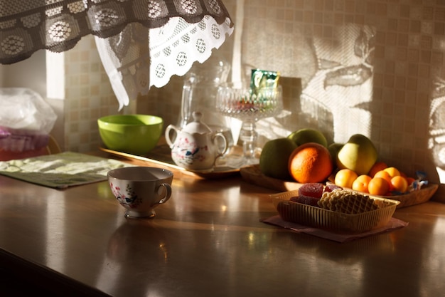 Variedade de frutas com chaleira e xícara na mesa na cozinha