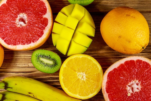 Variedade de frutas tropicais na mesa de madeira Ainda vida com bananas manga laranjas toranja e kiwis