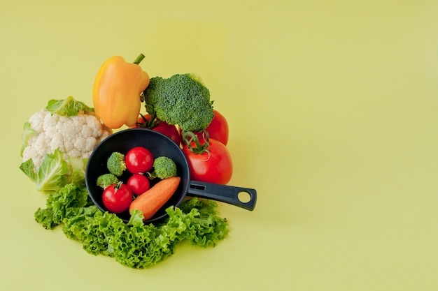 Variedade de legumes e frigideira em um quadro negro, vista superior. Conceito vegano e saudável.