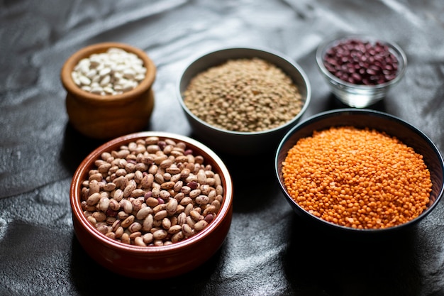 Variedade de legumes: feijão e lentilha. comida saudável crua. proteína vegetal. fundo escuro. fechar-se. espaço para texto