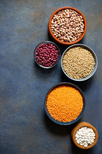 Variedade de legumes: feijão e lentilha. comida saudável crua. proteína vegetal. fundo escuro. vista do topo. espaço para texto