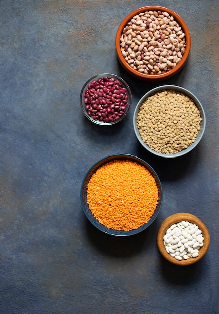 Variedade de legumes: feijão e lentilha. Comida saudável crua. Proteína vegetal. Fundo escuro. Vista do topo. Espaço para texto