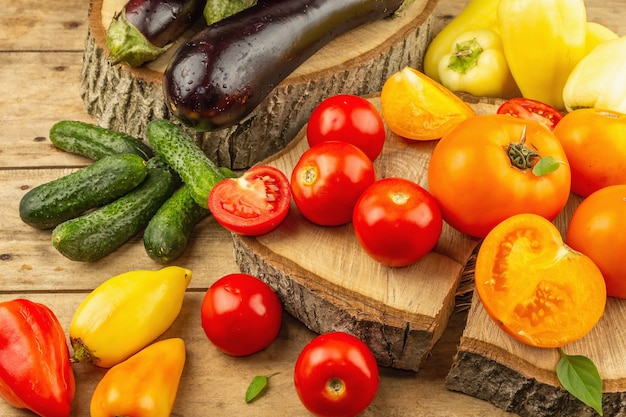 Variedade de legumes frescos em um fundo de madeira. Tomates maduros, berinjelas, pepinos e pimentões, vista superior