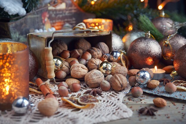 Variedade de nozes na decoração de natal e reveillon. composição de natal e ano novo com galhos de árvores de abeto, velas e luz de feriados em fundo de madeira
