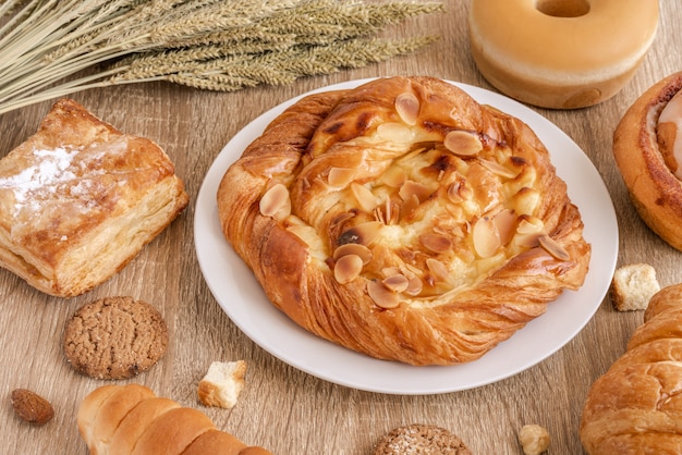 Variedade de pães, croissants, doces e trigos na superfície da mesa de madeira.