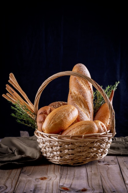 Variedade de pães na cesta na mesa de madeira no escuro