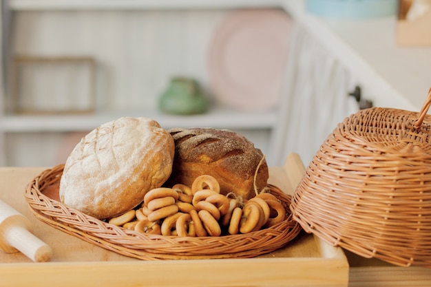 Variedade de pães perto de uma cesta de vime em uma mesa em uma cozinha rústica.