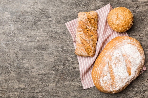 Variedade de pão fresco com guardanapo na mesa rústica vista superior Pão ázimo saudável Pão francês