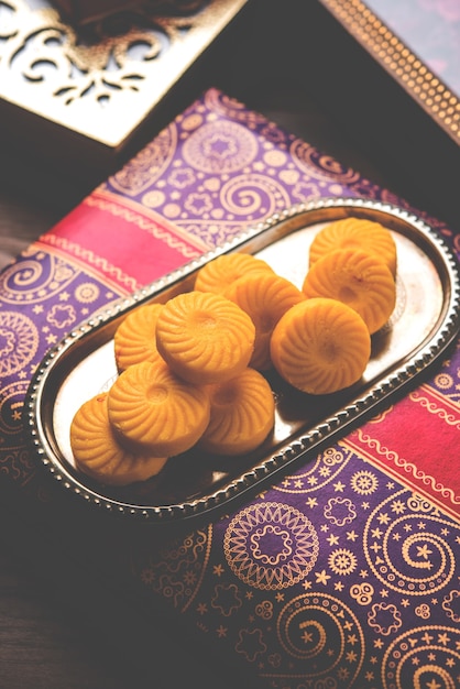 Variedade de Peda ou Pedha Servida em tigela ou prato sobre fundo branco ou com pilha de presentes. É um festival de comida popular da Índia. foco seletivo