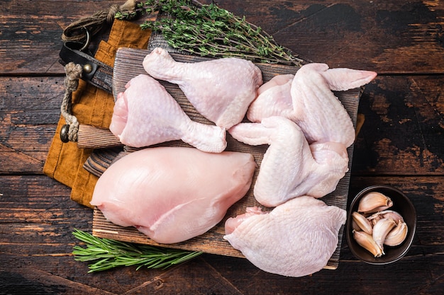 Variedade de porções de frango para churrasco Partes cruas sobrecoxa peito filé asas coxa Fundo de madeira Vista superior