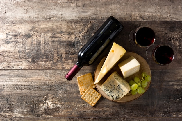 Variedade de queijos e vinho na mesa de madeira. vista do topo. copie o espaço