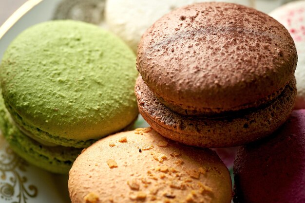 Variedade de sabores de bolos de macaroon em um prato branco sobre um fundo de madeira. Close up, foco seletivo