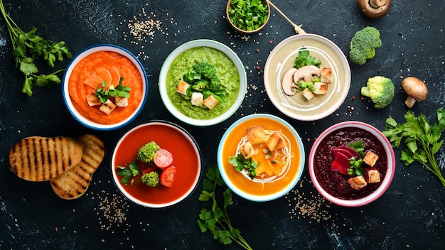 Variedade de sopas de creme de legumes coloridos Alimentos dietéticos Em um fundo de pedra preta Vista superior Espaço para cópia grátis