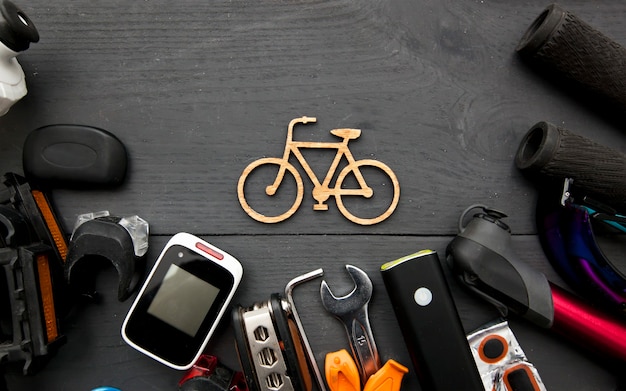 Vários acessórios de bicicleta diferentes em uma mesa de madeira ao redor de um pequeno ícone de bicicleta