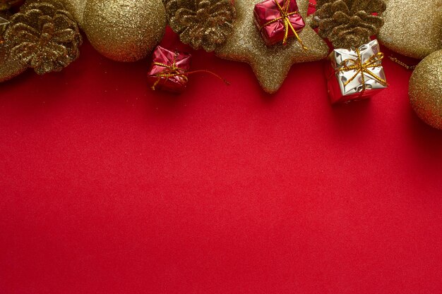 Varios adornos navideños dorados sobre fondo rojo.