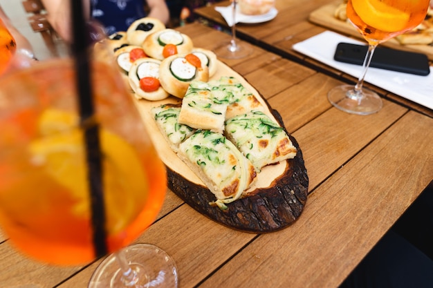 Varios aperitivos con aperol spritz cocktail en mesa de madera en un café.