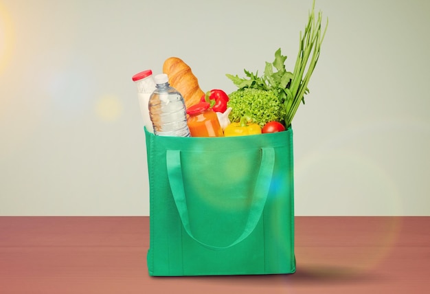 Varios artículos comestibles en bolsa sobre la mesa. Bolsa de comida con verduras frescas