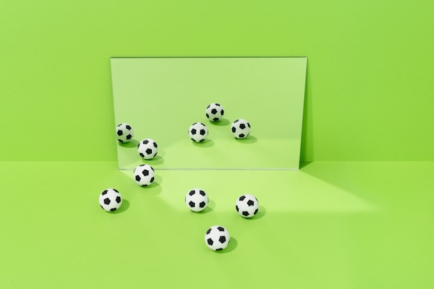 Varios balones de fútbol se reflejan en un espejo sobre un fondo verde. concepto de fútbol y deporte.