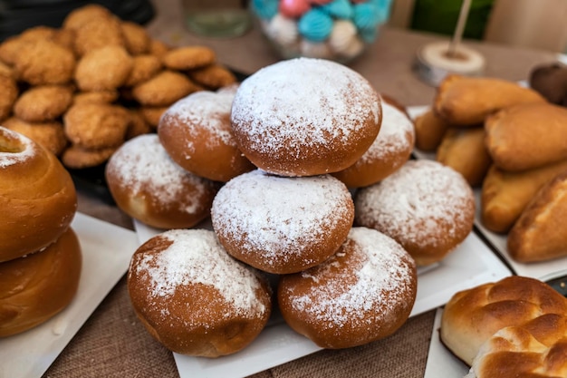 Varios bollos sobre la mesa en tobogán cubiertos con pasteles dulces de azúcar en polvo con azúcar en polvo