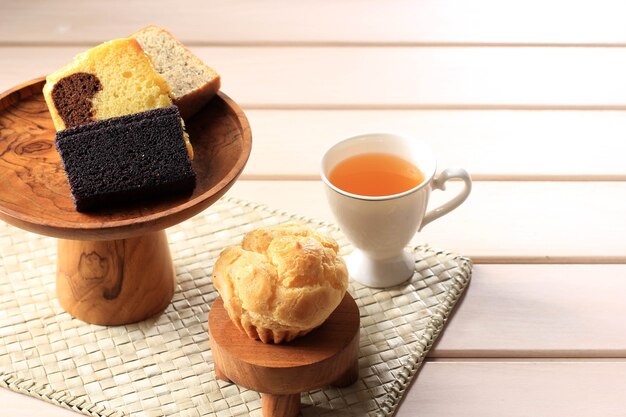 Vários bolo de fatia para caixa de lanche da indonésia. choux, bolo de banana, bolo de mármore e bolo de arroz pegajoso preto. servido com chá. copie o espaço no fundo de madeira