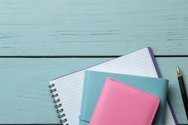 Vários cadernos e caneta sobre uma mesa de madeira azul clara. vista do topo. ferramentas de escritório