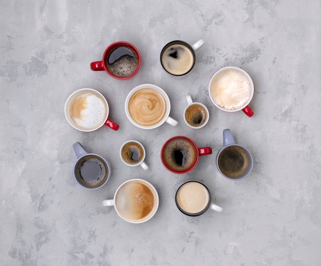 Varios cafés en diferentes tazas sobre la mesa de concreto gris