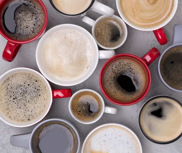 Foto varios cafés en diferentes tazas sobre la mesa de concreto gris