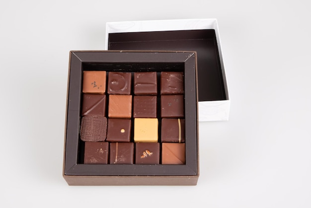 Varios caramelos de praliné de chocolate de variedad fina cuadrada en pequeña caja de regalo