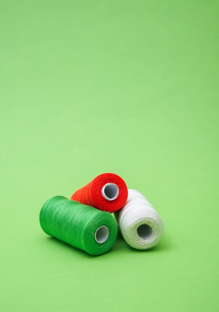 Foto vários carretéis de fios de algodão de costura de diferentes cores bandeira italiana em fundo verde