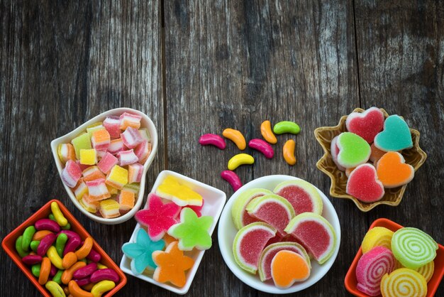 Varios colores dulces azucarados en contenedor en tablón de madera vieja