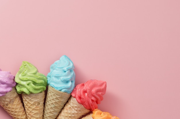 Varios de colorido cono de helado de merengue sobre fondo rosa para el concepto de postre dulce y refrescante