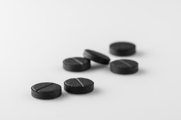 Vários comprimidos de carvão ativado médico preto sobre fundo branco. Isolado