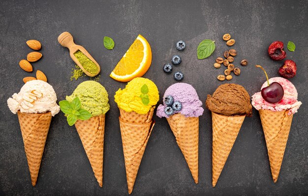 Foto vários de sabor de sorvete em cones mirtilo chá verde pistache amêndoa laranja e cereja configuração em fundo de pedra escura verão e doce conceito de menu